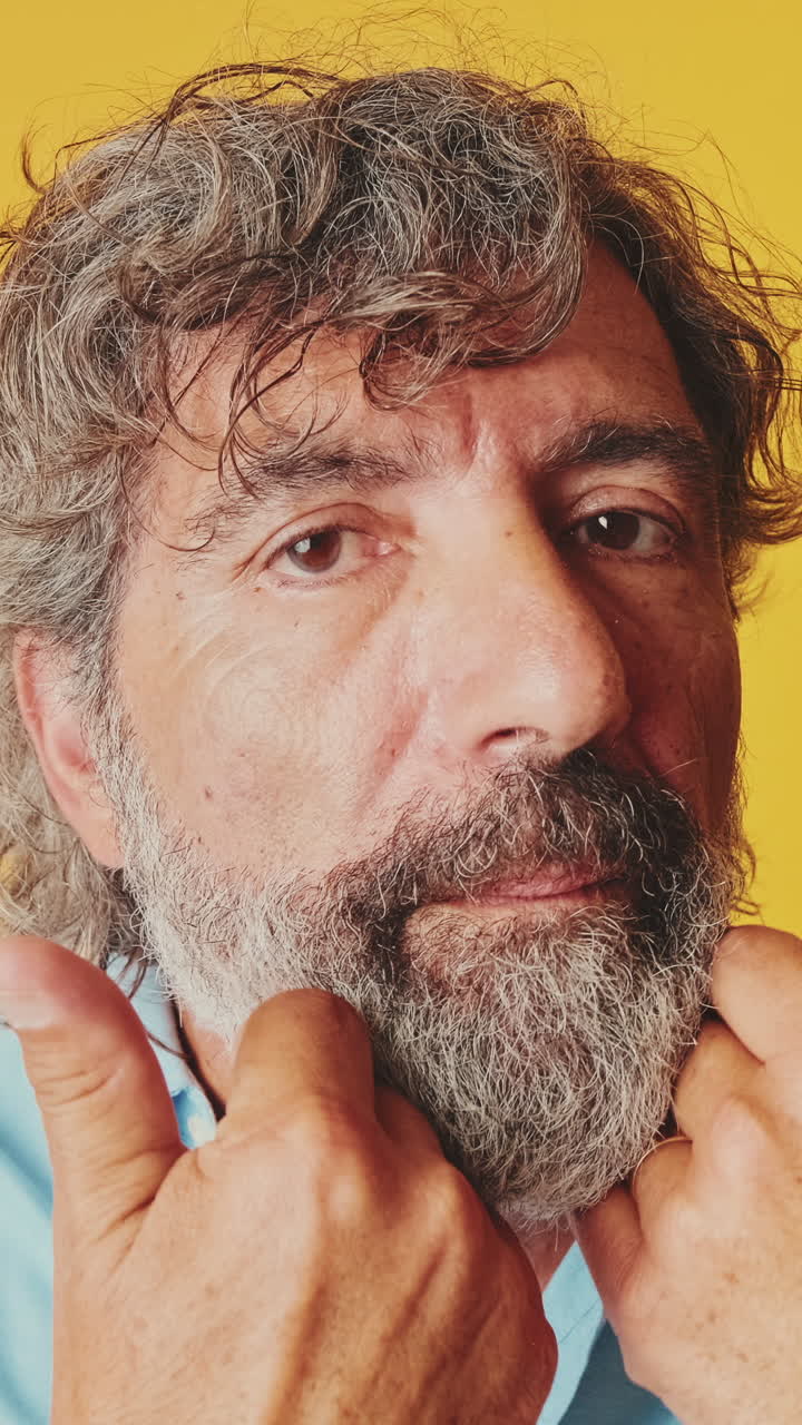 Primo piano di un uomo maturo con la barba che si tocca il viso