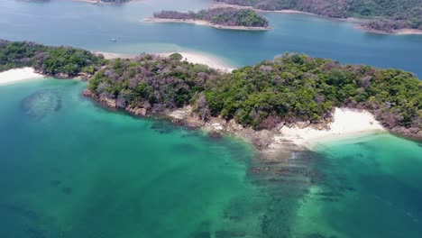 Strafe-Aerial-of-Pacific-Island-with-White-Beach-and-Unique-Coral-and-Rock-Formations