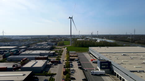 flying towards spinning windmill at the edge of industrial zone