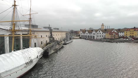 low alititude aerial footage from the side of hms jarramas and two military ships next to a museum