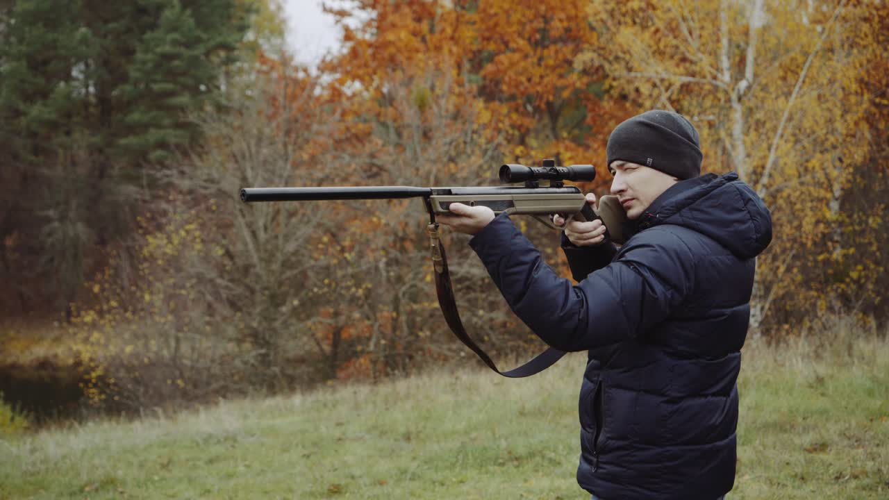 Man shooting gun in forest. Close up of male hunter in the forest aiming and shooting with hunting rifle
