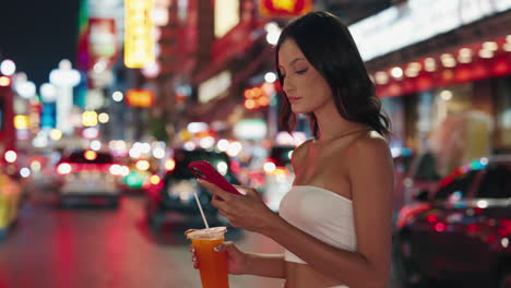 woman enjoying a drink on a busy night street