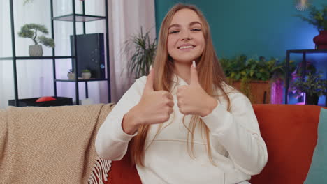 happy young woman looking approvingly at camera showing thumbs up, like positive sign, good news