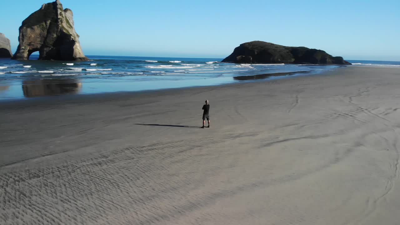 hombre de pie en una playa de arena intacta, disfrutando de una vista espectacular de las islas de arcos naturales