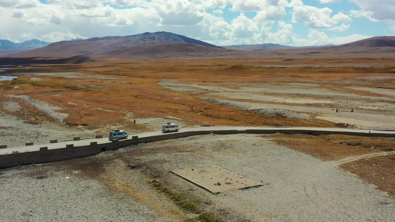 drone aéreo de camionetas que transportan carga y turistas cruzando un puente en la llanura alpina de gran altitud del parque nacional deosai ubicado entre skardu y el valle de astore en pakistán en un día soleado de verano