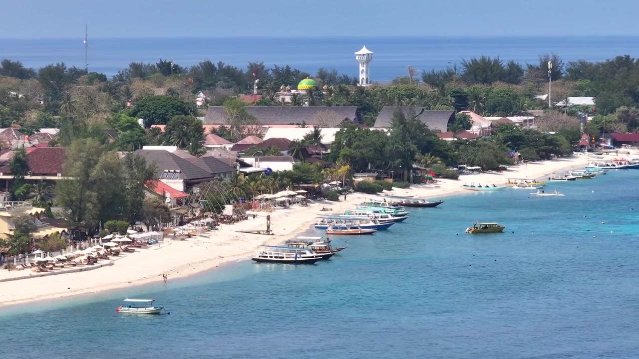 Kaunis hiekkaranta, pieni satama ja rakennuksia Gili Trawanganin saarella, Indonesiassa - drone