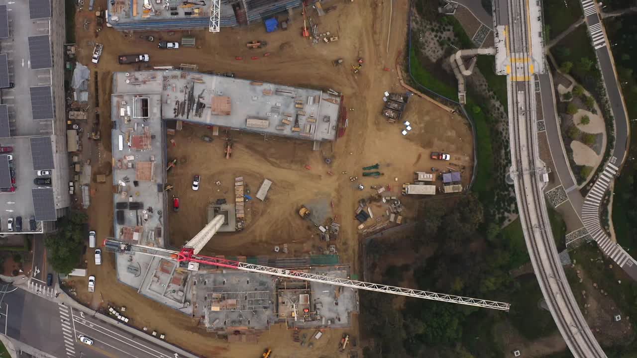 vista de un avión no tripulado hacia abajo de un gran sitio de construcción con una gran grúa moviéndose por debajo