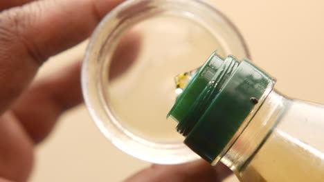 pouring oil from a green bottle into a glass