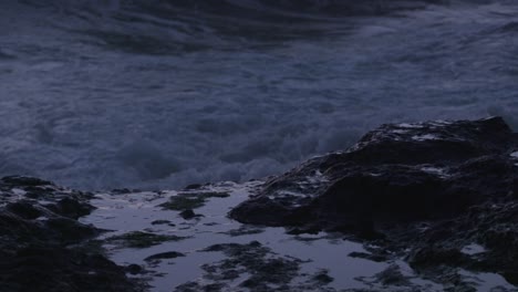 extreme close-up: ocean spray jets up behind rocky tide pool. filmed at sunset on the oregon coast.