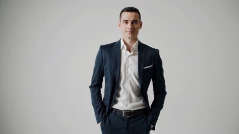 professional man in a dark suit standing with hands in pockets