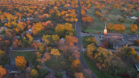 flyover charming small town street in ladue, missouri near a church and with a lot of trees in autumn at sunset