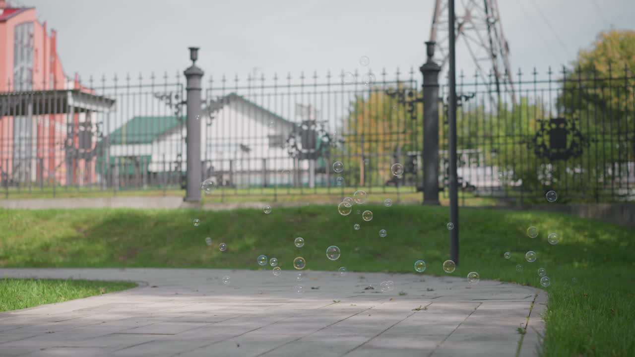 Joie estivale avec des bulles flottantes : des bulles colorées dérivent doucement dans un décor estival extérieur lumineux. Scène joyeuse avec des bulles de savon flottant au-dessus d’un trottoir ensoleillé près de pelouses verdoyantes et paisibles.