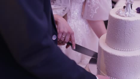 bride and groom is cutting their wedding cake. hands cut of a slice of a cake