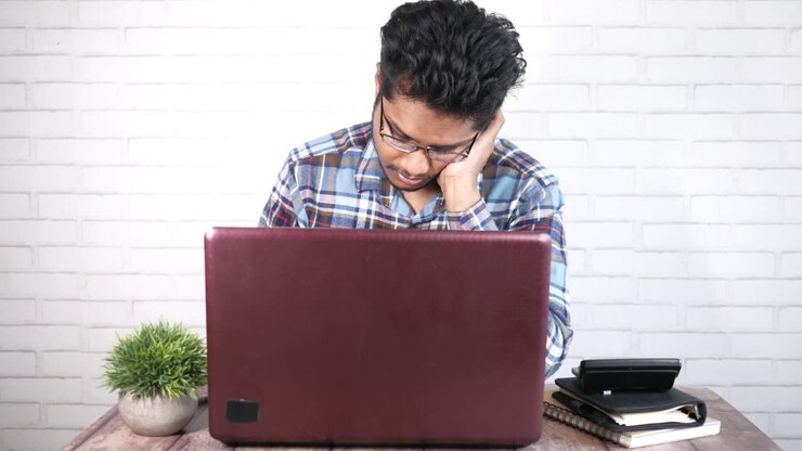 Mann arbeitet an einem Laptop am Schreibtisch