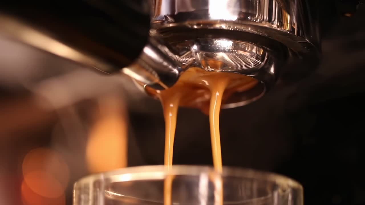 Primo piano video di caffè espresso che cola da una macchina in un bicchiere, catturando la ricca consistenza