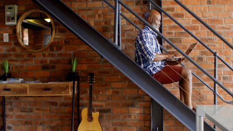 senior man using laptop on stairs in living room 4k