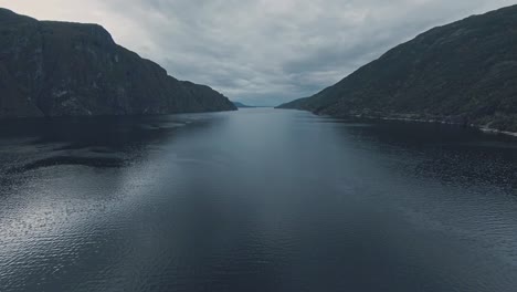 vast lake water with rocky mountains around, aerial drone view