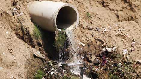 sewage or drainage water flowing from concrete pipe into polluted land. concept of water pollution, urban waste and environmental hazards. ideal for documentaries or awareness campaigns.