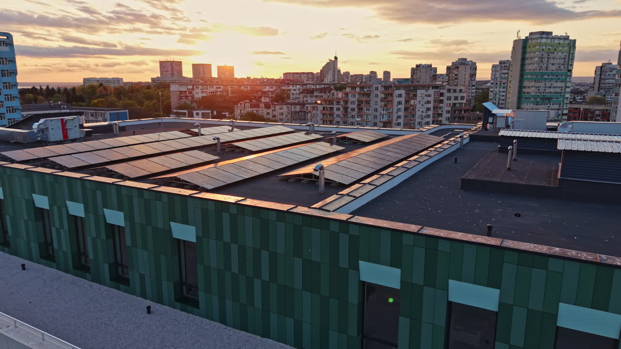 Solar panels on a rooftop with buildings and sunset in the background