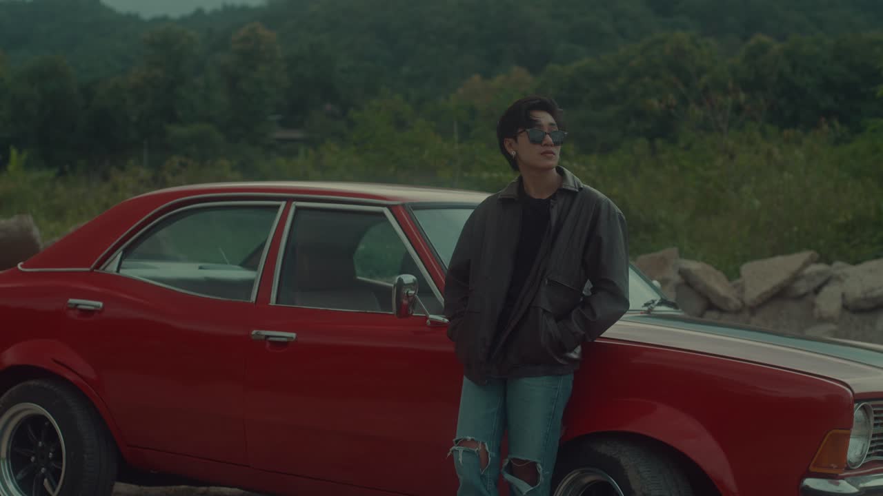Person leaning against a classic red car