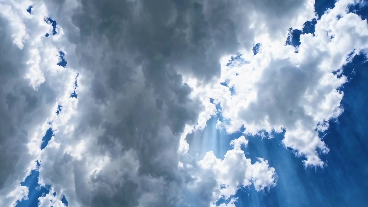 Raggi di sole che filtrano attraverso nuvole in movimento nel cielo blu