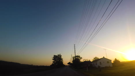 car driving through a farming community at sunset