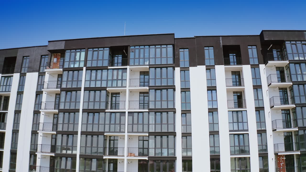 Front view of a beautiful multi-storey building. Modern design of high-raised apartment building with many glass windows and balconies. Aerial view.