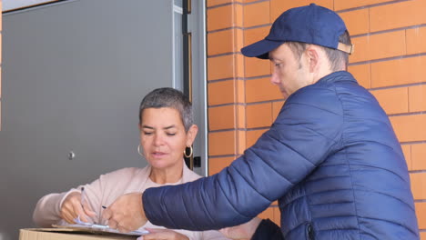 mujer que firma para recibir un paquete en el portapapeles en su casa