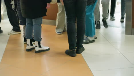 the lower half of various people standing and moving in a mall. the image focuses on different legs and footwear, highlighting a busy indoor environment with diverse individuals