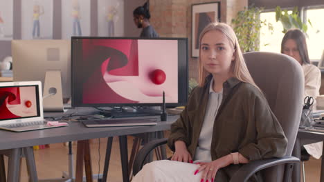 female graphic designer looking at camera while sitting in an office chair in animation studio