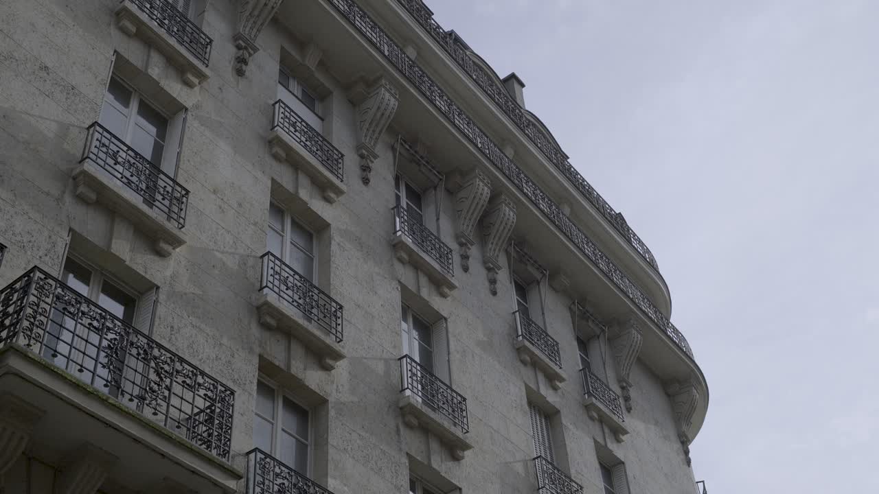 Building facade in Paris with balconies, historical architecture, and cloudy sky