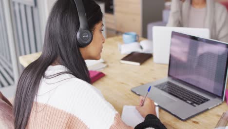 Vídeo-De-Una-Mujer-Birracial-Enfocada-Con-Auriculares-Aprendiendo-Con-Una-Computadora-Portátil-En-Casa