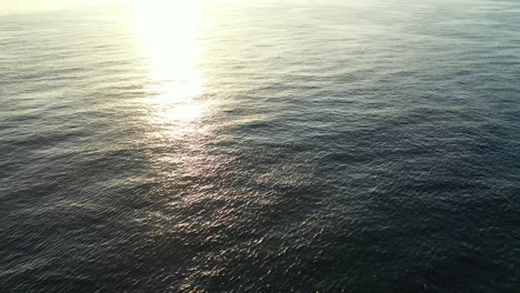 vuelo aéreo sobre un vasto cuerpo de agua, con el hermoso sol de la tarde brillando en las ondas