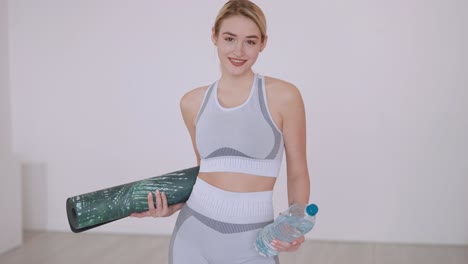 woman doing yoga with water bottle and mat