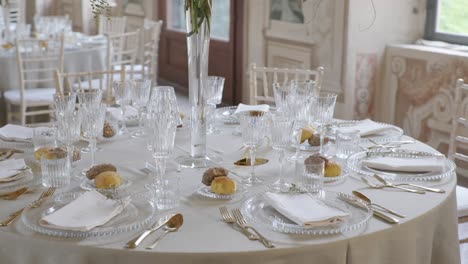 4k órbita alrededor de la mesa de la cena de la boda bellamente decorada con cubiertos de clase, vasos, pan y arreglo de flores