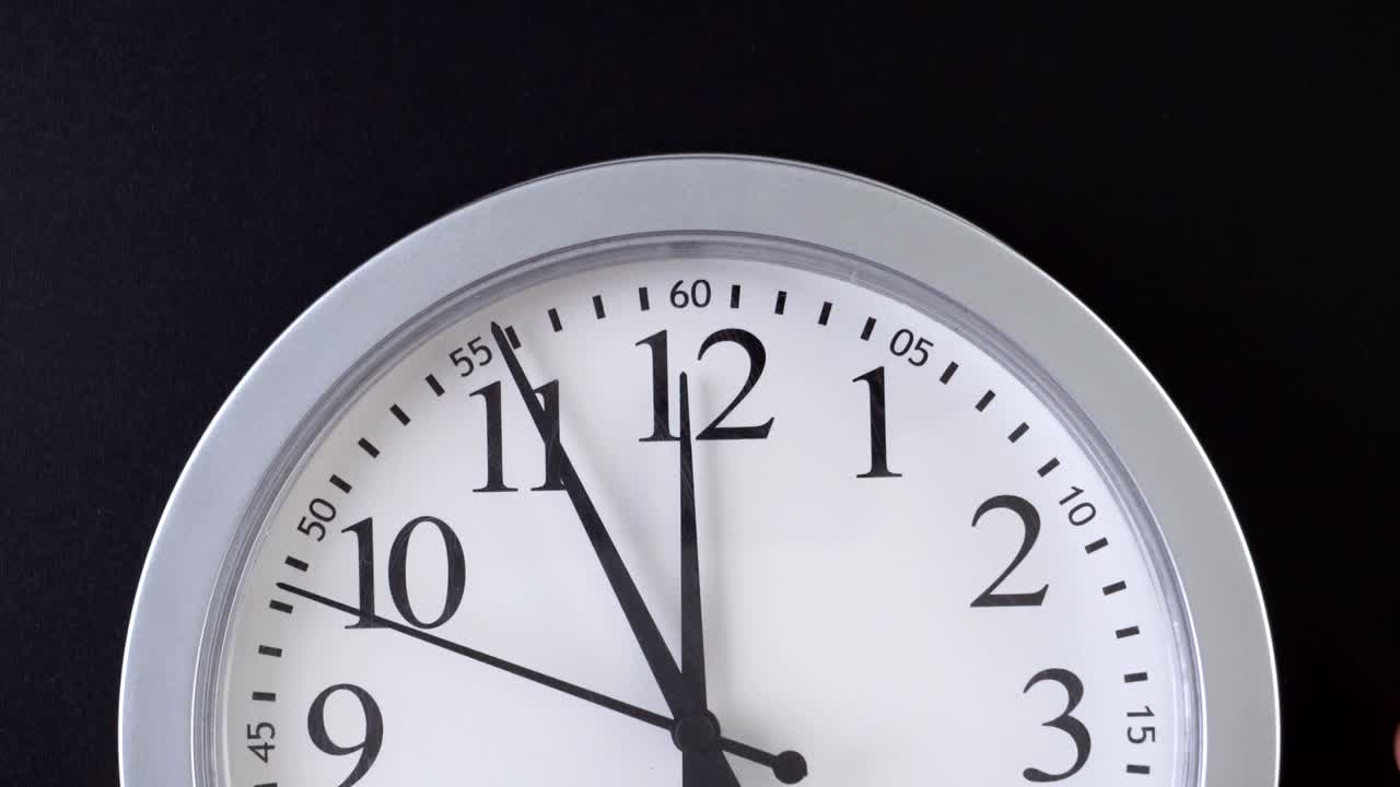 Semplice orologio da parete rotondo su sfondo nero.