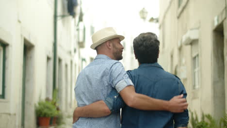 pareja gay abrazándose la cintura y caminando por la ciudad