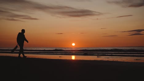man running with guitar in back sand beach at sunset