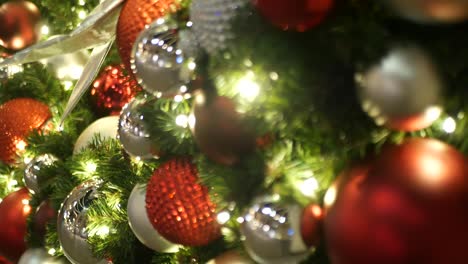 closeup of festively decorated outdoor christmas tree with bright red balls on blurred sparkling fairy background. defocused garland lights, bokeh effect. merry christmas and happy holidays concept.