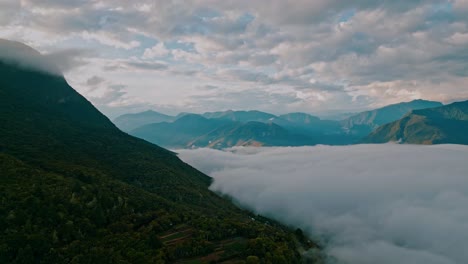 Drone-footage,-where-a-portion-of-the-majestic-mountain-range-is-shrouded-in-clouds,-and-terraced-agricultural-fields-showcase-human-ingenuity-amid-the-serene,-verdant-landscape