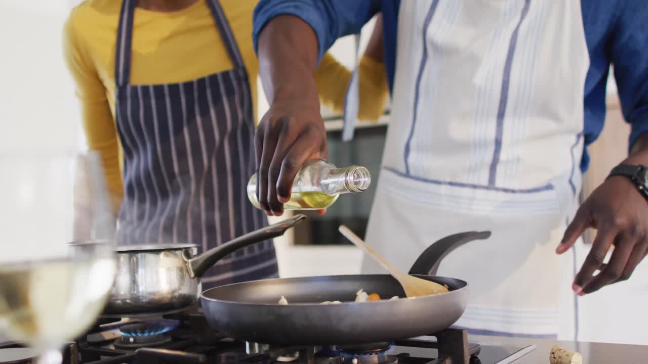 Video of midsection of african american couple cooking together