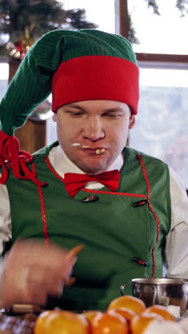 elf eating at a table. santas elf eating christmas dinner in a decorated room. new year celebration. christmas eve. vertical video