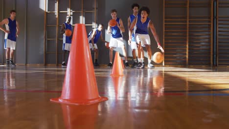 diverse male basketball team wearing blue sportswear practice dribbling ball