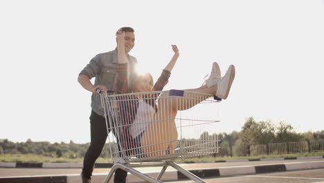 young friends having fun on shopping trolleys. multiethnic young people racing on shopping cart. slow motion