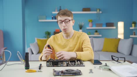 Young man interested in electronic board looks at camera and makes positive gesture.