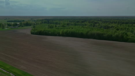 A-recently-ploughed-field-next-to-a-field-of-trees-is-ready-for-sowing