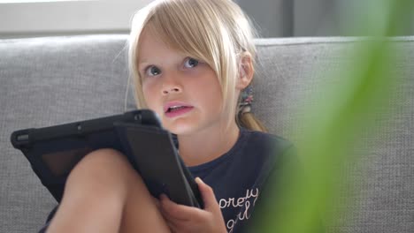 young white blonde pretty girl playing with tablet computer inside