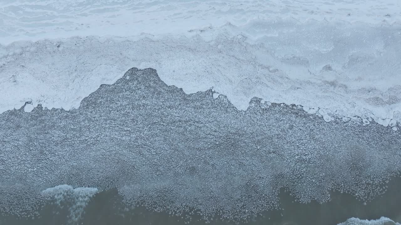 얼어붙은 호수 연안에 부드러운 파도가 는 차가운 날의 평온은 파란색의 색조로 포착됩니다.