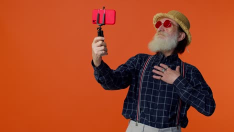 mature grandfather traveler blogger in sunglasses, taking selfie on mobile phone, video call online