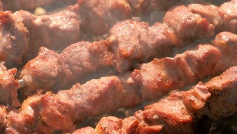 la apetecible y jugosa barbacoa de cerdo se asada en salchichas encima de la parrilla de carbón. piezas de carne de primer plano.